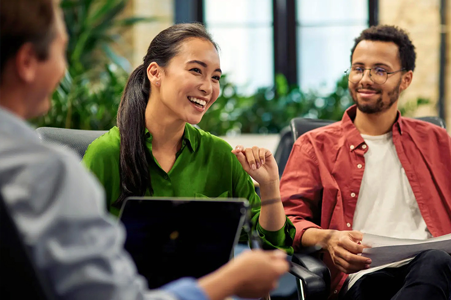 Coworkers laughing together during a meeting in an office with a laptop and papers